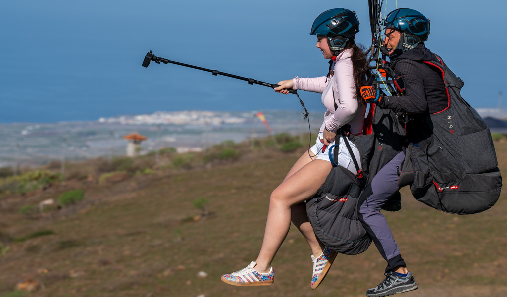 Zwei Personen gleiten mit Gleitschirm über eine Landschaft von Teneriffa.