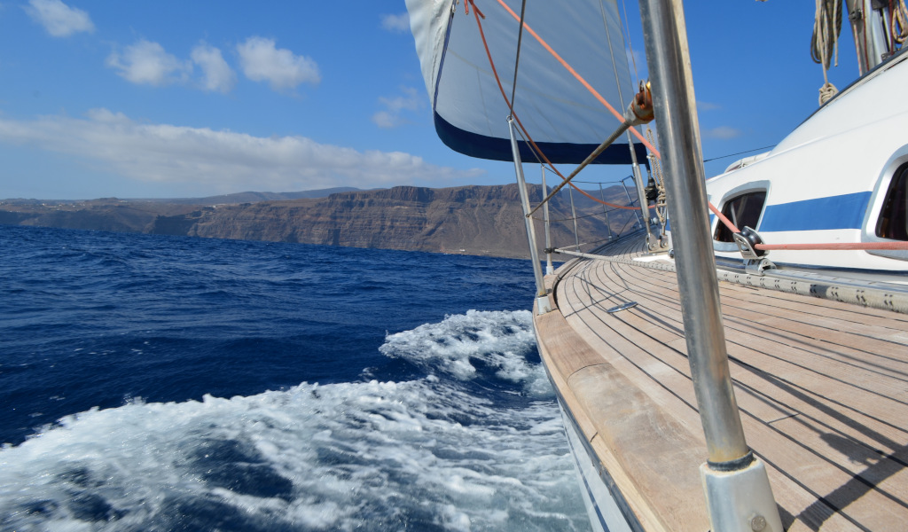 Segelboot segelt nahe der Küste Teneriffas mit Bergen im Hintergrund.