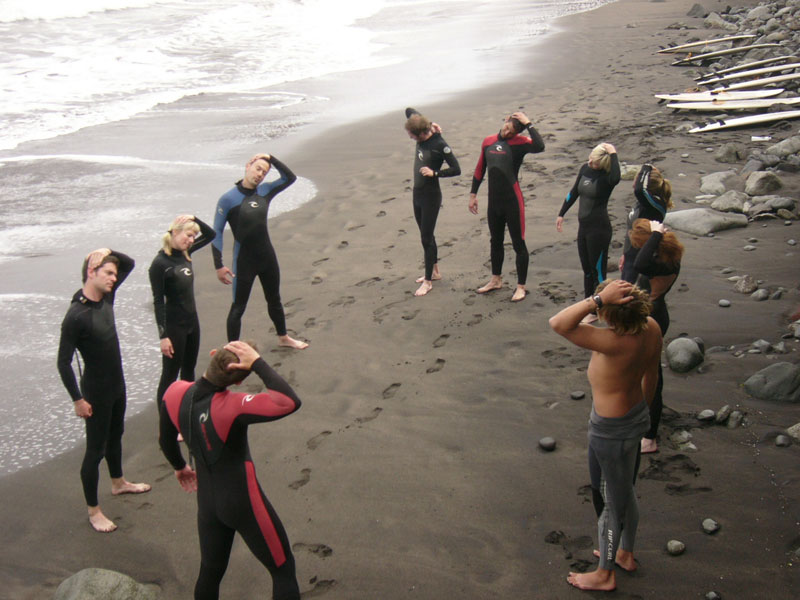 Menschen in Neoprenanzügen trainieren am Strand auf Teneriffa.