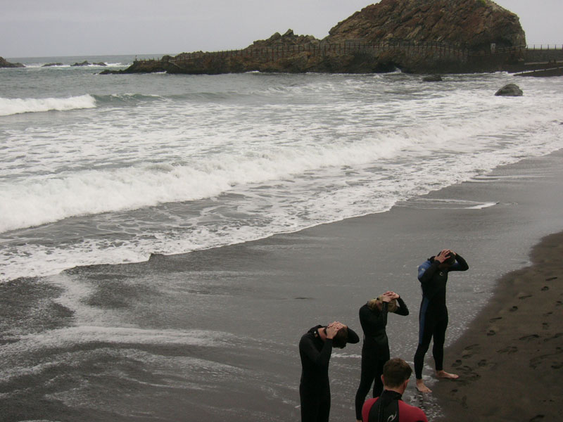 Menschen in Neoprenanzügen am Strand El Roque de las Bodegas, Teneriffa.