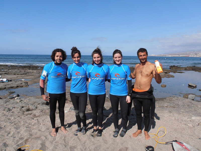 Gruppe von Surfern am Strand auf Teneriffa in blauen Neoprenanzügen.