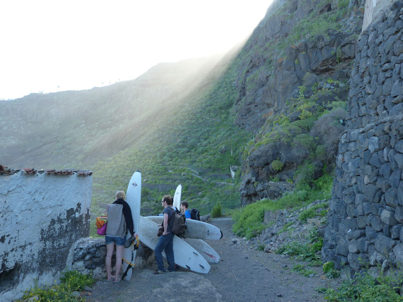 Menschen mit Surfbrettern, die auf einem Pfad auf Teneriffa spazieren, umgeben von Bergen.
