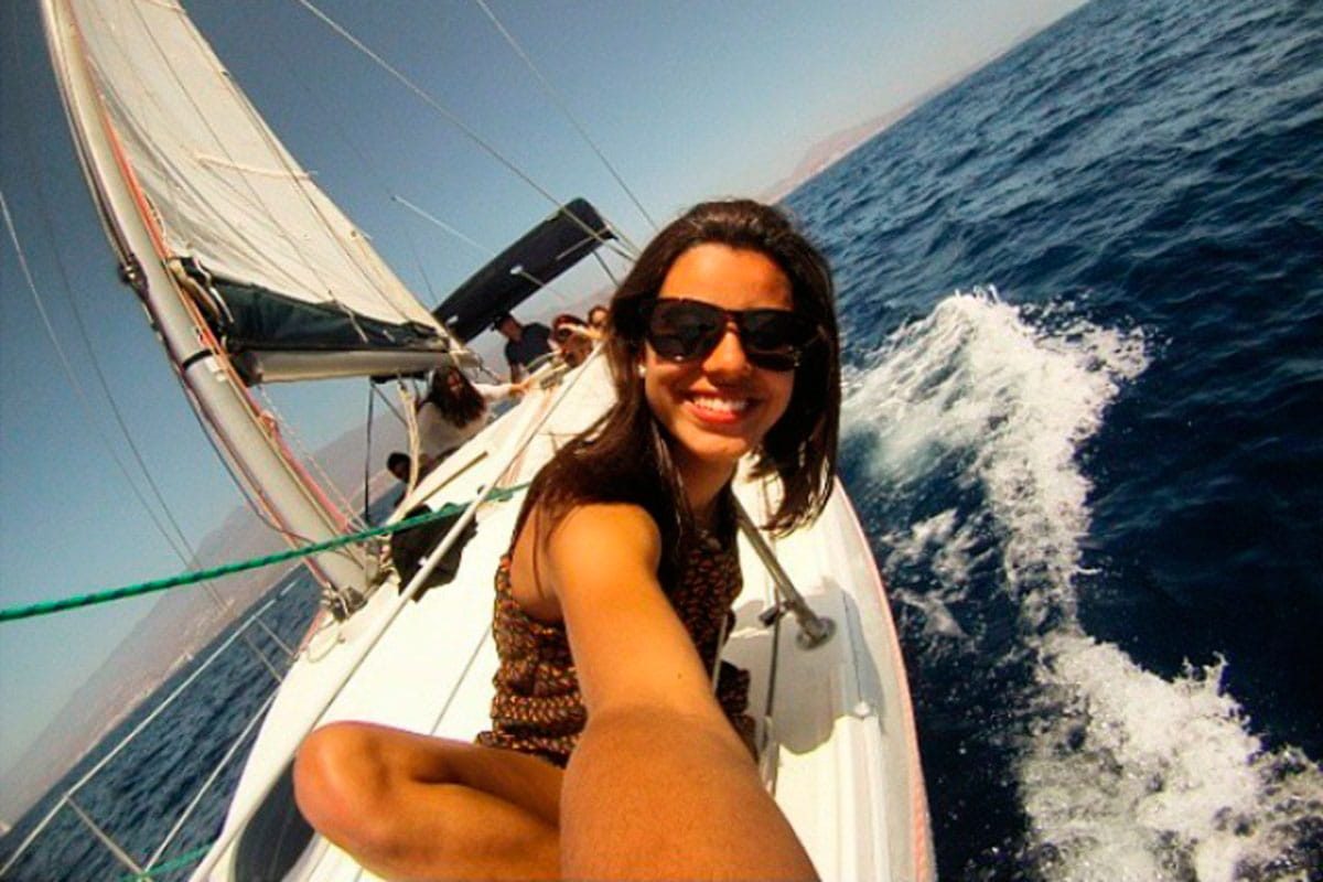 Person, die auf einem Segelboot in der Nähe der Küste Teneriffas lächelt.