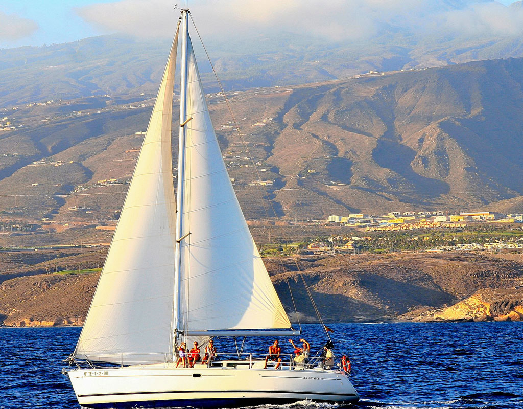 Segelboot segelt nahe der Küste Teneriffas mit Bergen im Hintergrund.