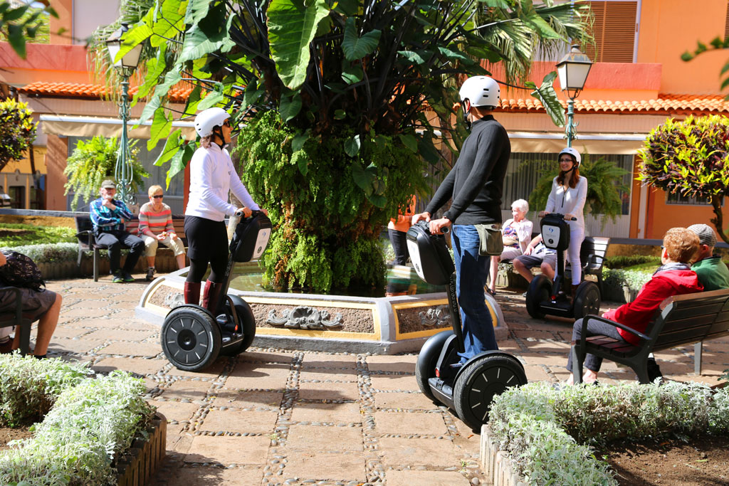 Menschen auf Segways um einen Brunnen auf einem Platz auf Teneriffa.