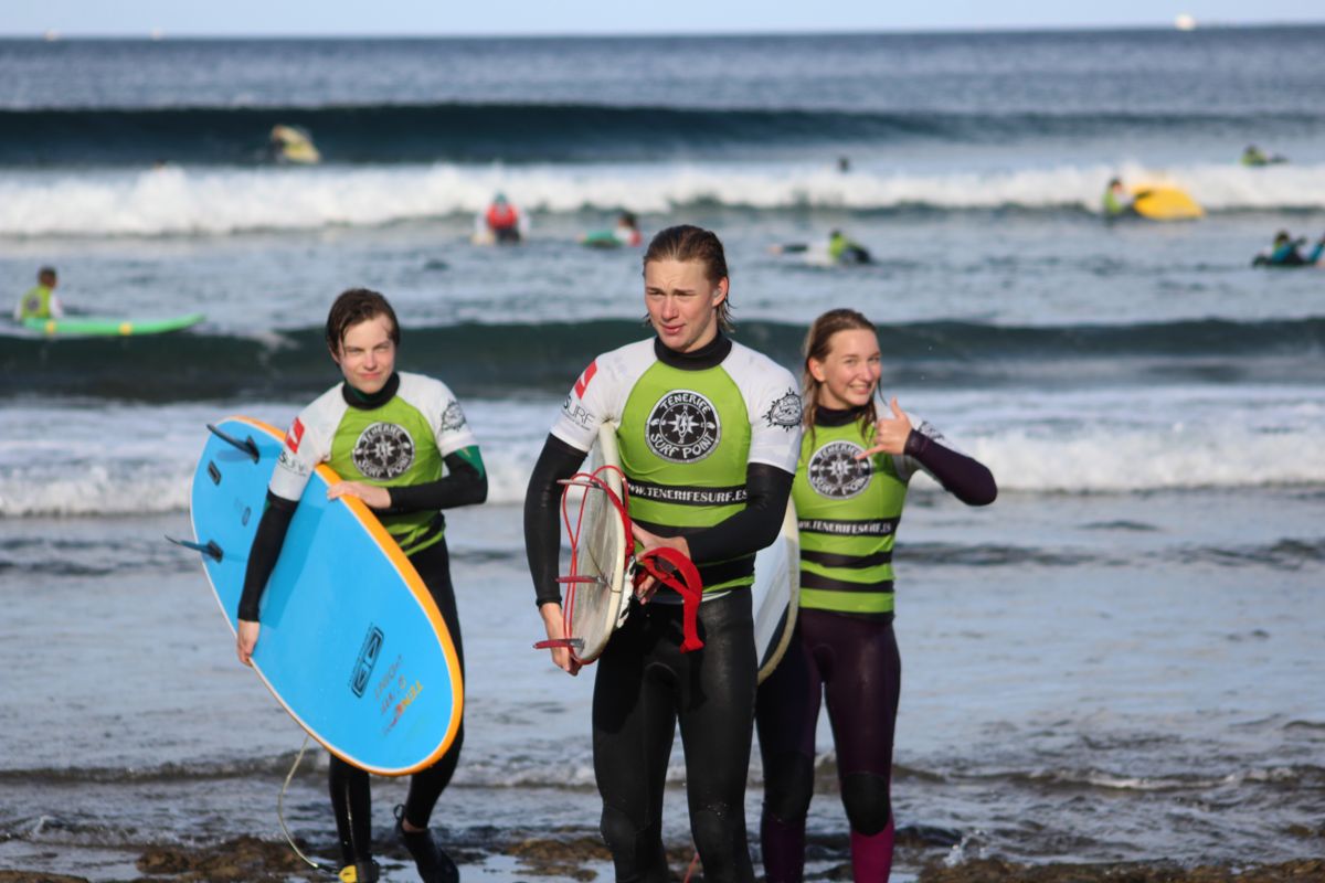 Surfer am Strand auf Teneriffa, mit Boards und Neoprenanzügen, in Meeresnähe.
