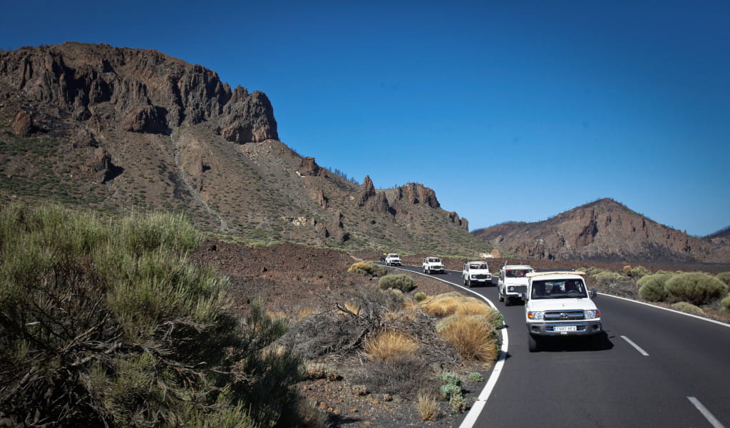 Karawane von Autos auf der Straße zum Teideberg, Teneriffa, umgeben von Bergen.