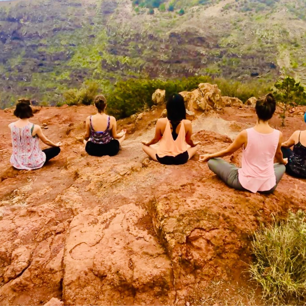 Menschen, die draußen auf einer Klippe auf Teneriffa meditieren.
