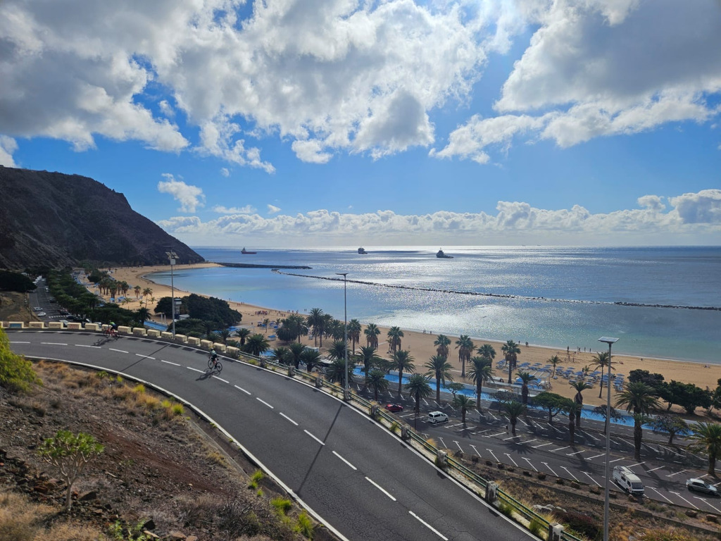 Der Strand Las Teresitas auf Teneriffa mit Radfahrern auf der Straße und Meerblick.