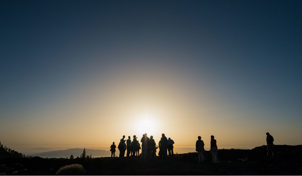 Menschen, die den Sonnenaufgang an einem Aussichtspunkt auf Teneriffa beobachten.
