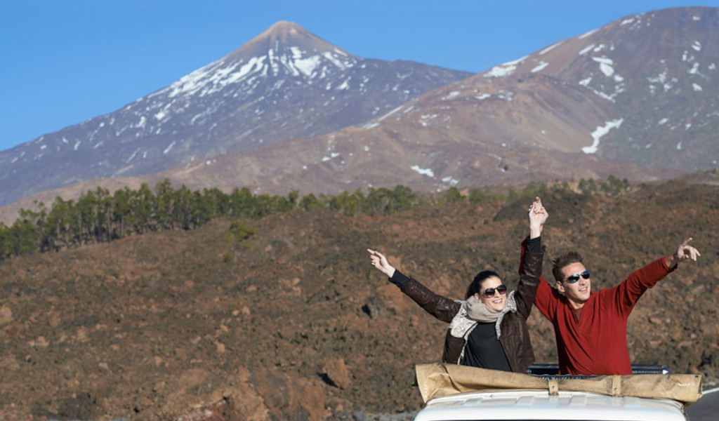 Lächelnde Menschen in einem Jeep vor dem Teide-Berg auf Teneriffa.