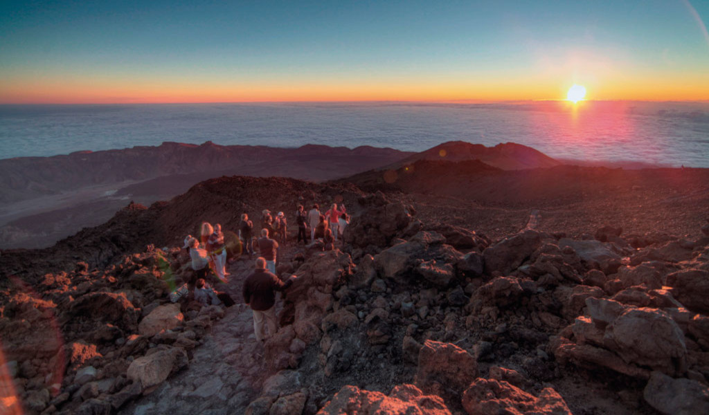 Eine Gruppe von Menschen, die den Sonnenaufgang auf dem Teideberg, Teneriffa, beobachtet.