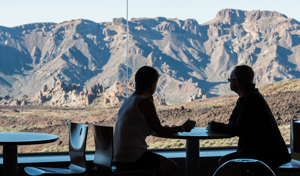 Zwei Personen sitzen in einem Café mit Blick auf den Nationalpark Teide auf Teneriffa.