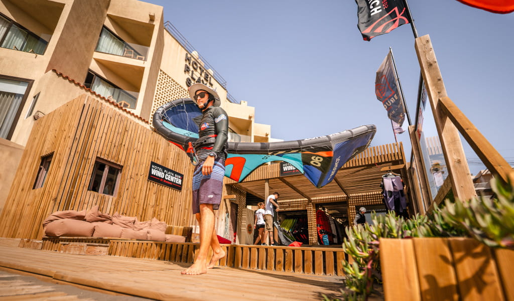 Person, die Windsurfausrüstung im Hotel Playa Sur auf Teneriffa hält.
