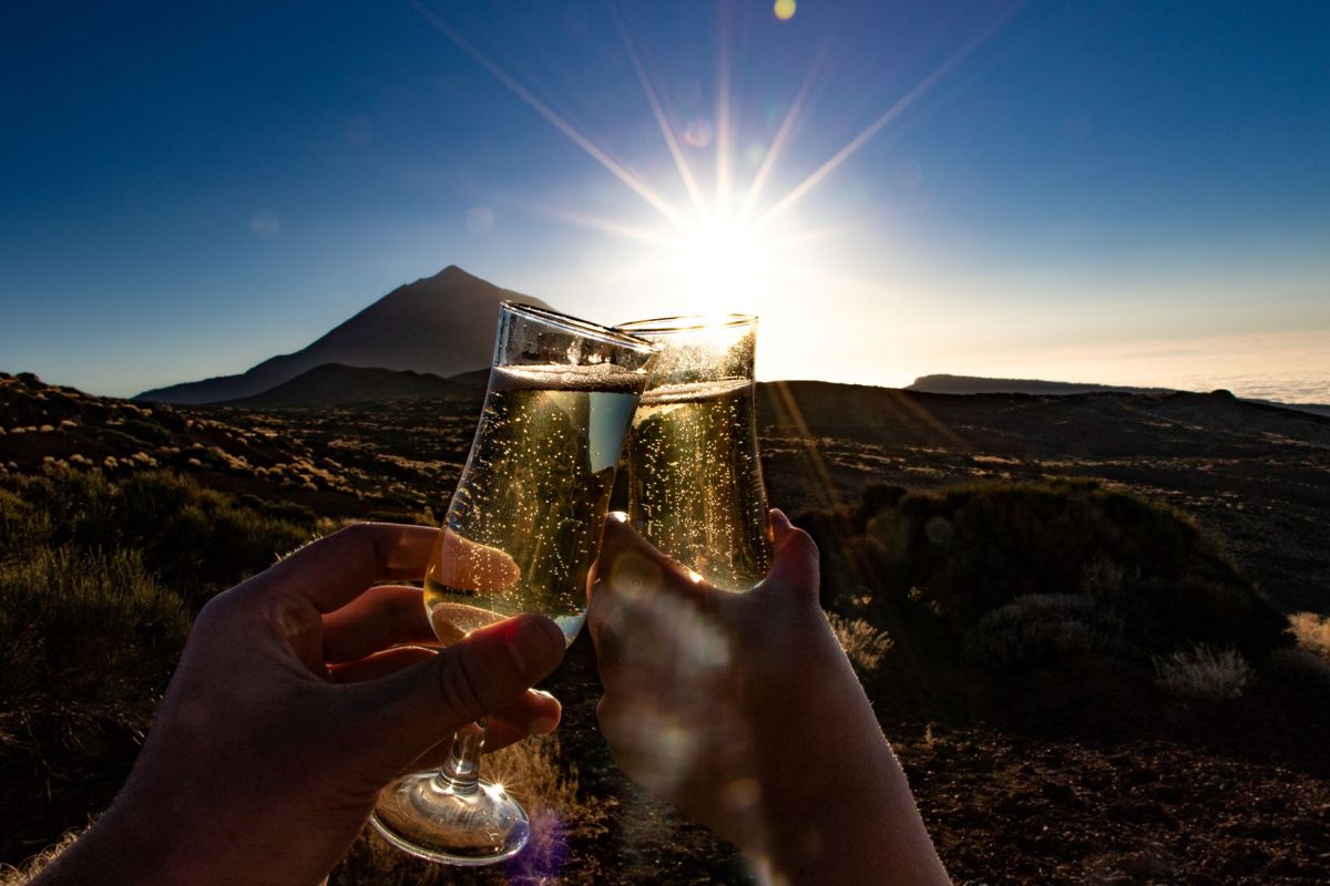 Stoßen Sie mit Gläsern Champagner bei Sonnenuntergang nahe dem Teide auf Teneriffa an.