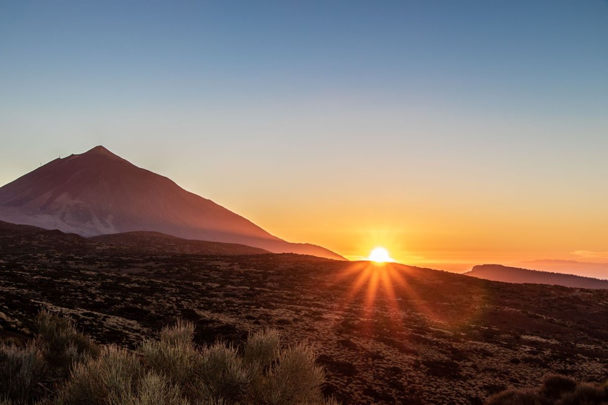 Sonnenaufgang auf dem Teideberg, Teneriffa, mit der Sonne, die hinter dem Horizont hervorlugt.