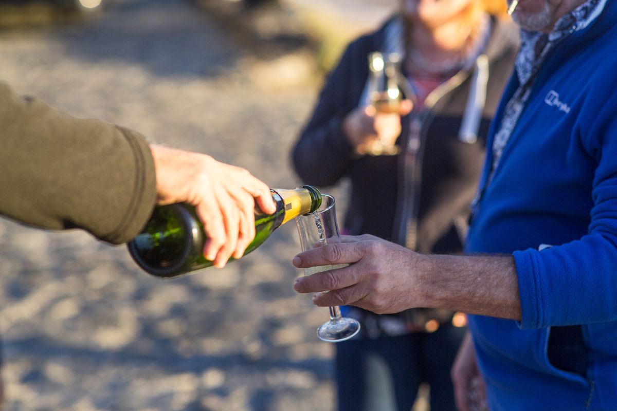 Champagner in ein Glas am Strand auf Teneriffa gießen.