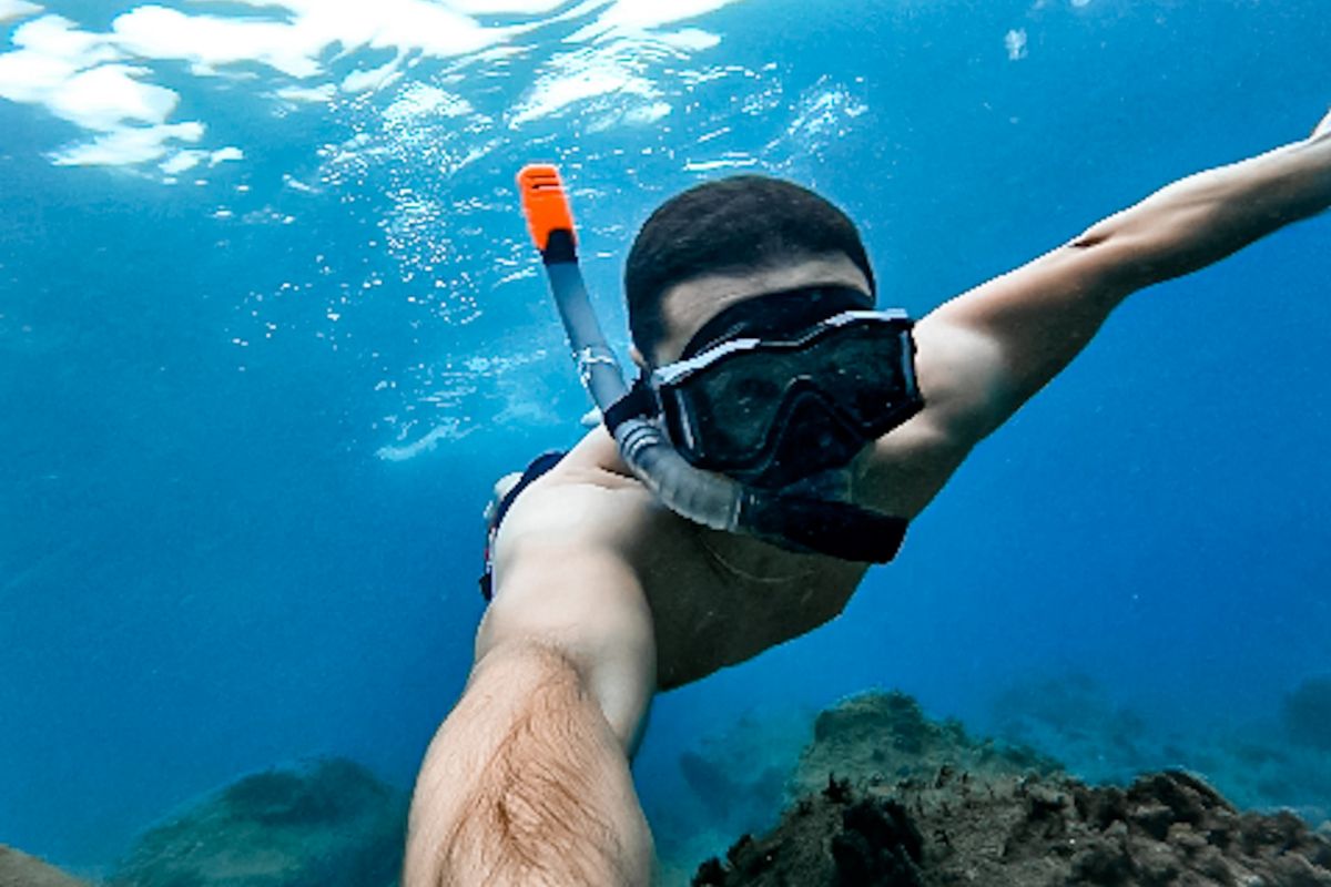 Person, die in kristallklarem Wasser in der Nähe von Teneriffa taucht.