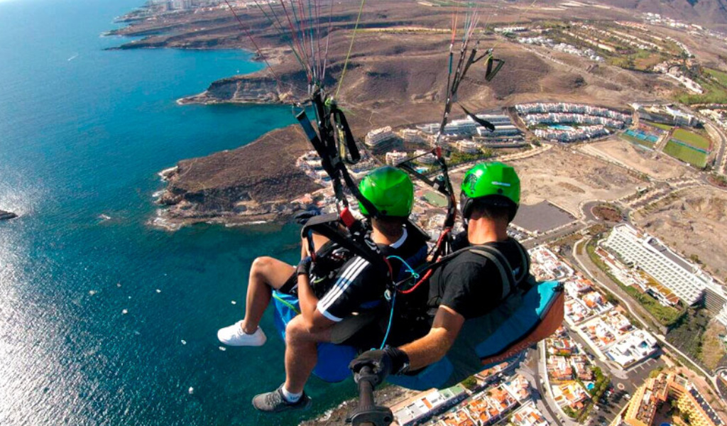 Menschen gleiten über die Küste Teneriffas mit Luftaufnahme vom Meer und den Gebäuden.