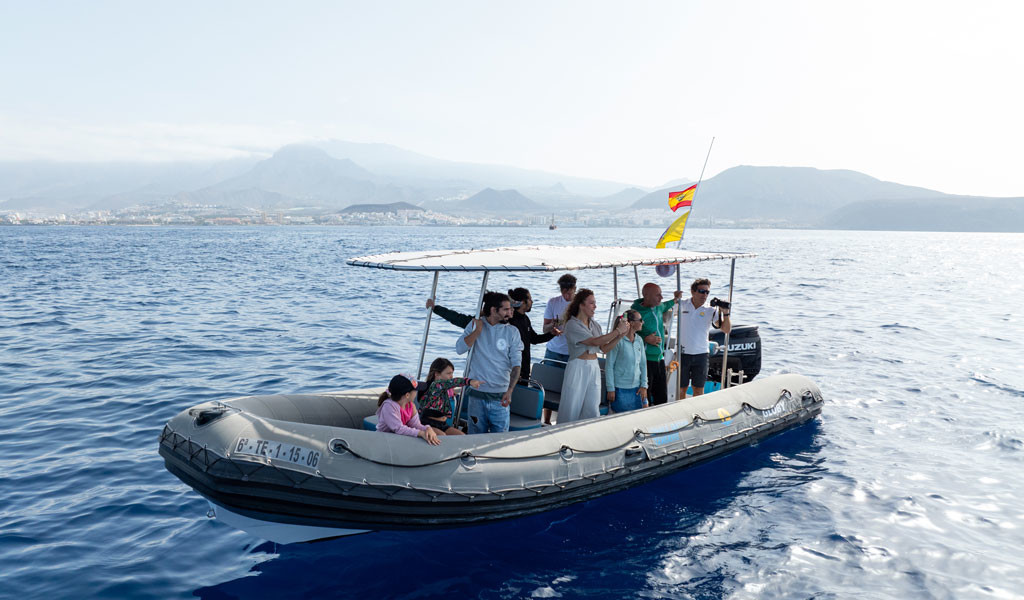 Menschen auf einem Boot im Meer bei Teneriffa mit Bergen im Hintergrund.