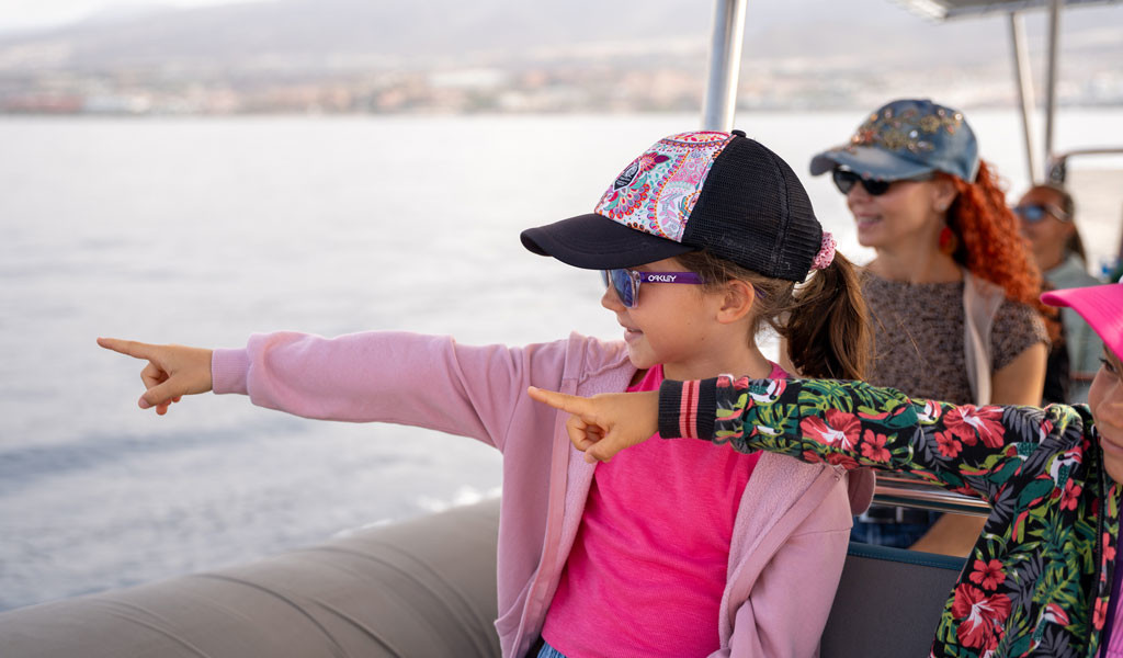 Mädchen, die von einem Boot an der Küste Teneriffas zeigen.