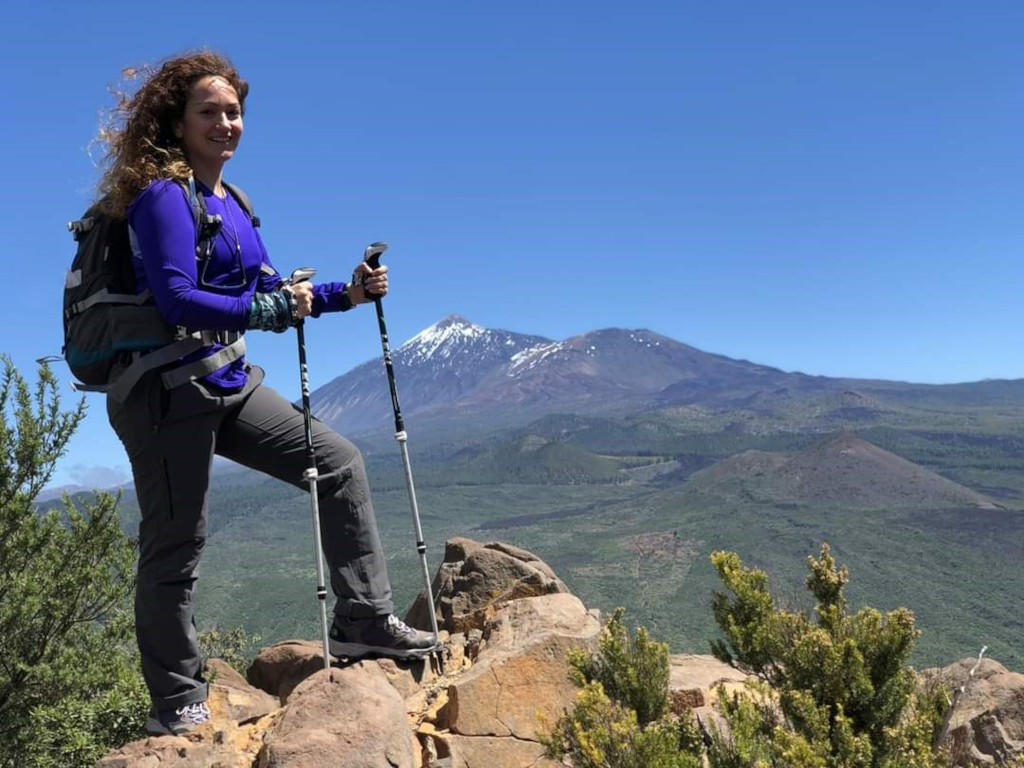 Wanderer mit Stangen auf einem felsigen Pfad mit dem Teide im Hintergrund, Teneriffa.