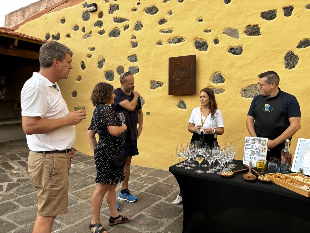 Eine Gruppe von Menschen bei einer Weinverkostung auf Teneriffa, neben einem Tisch mit Getränken und Snacks.