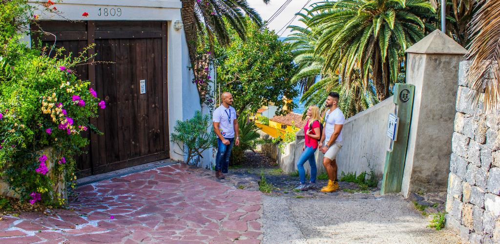 Drei Menschen reden auf einer von Palmen umgebenen Straße auf Teneriffa.