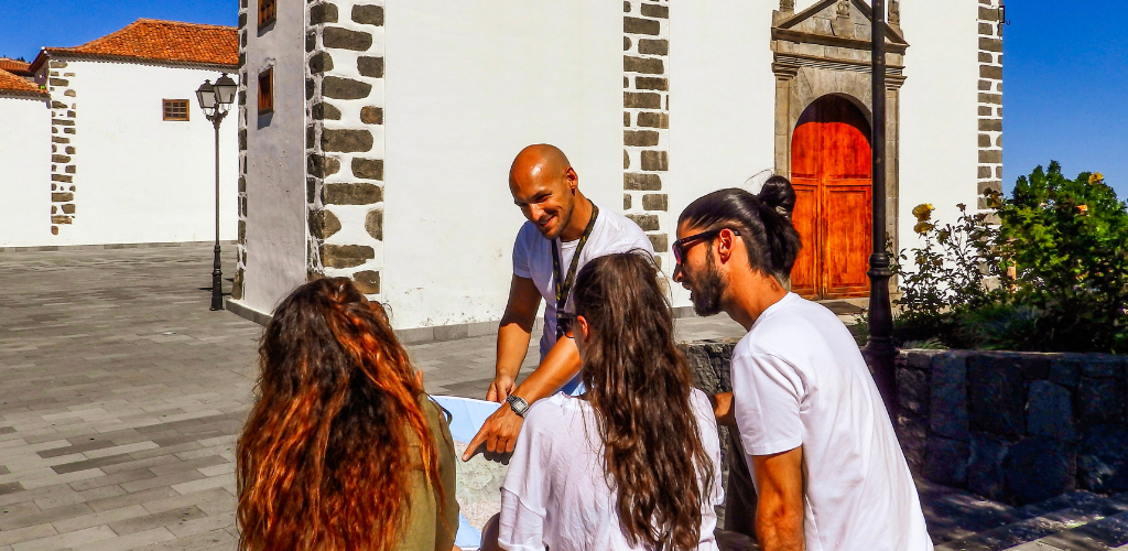 Eine Gruppe von Menschen, die eine Karte vor einer Kirche in La Laguna, Teneriffa, betrachten.