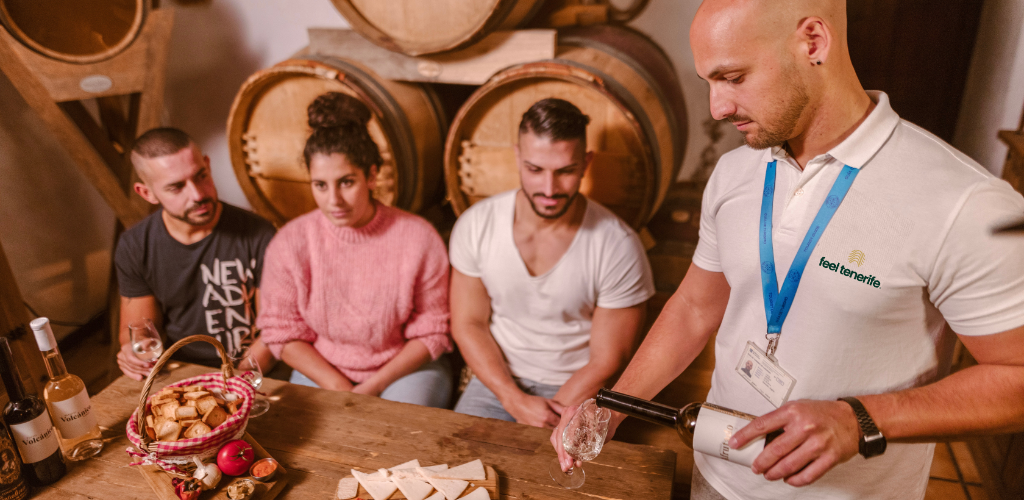 Der Guide serviert drei Personen Wein in einem Weingut auf Teneriffa.
