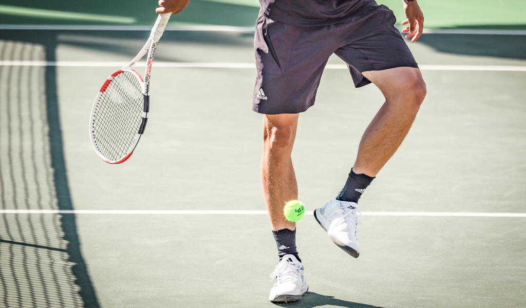 Tennisspieler auf einem Platz auf Teneriffa, der mit seinem Schläger einen Ball schlägt.