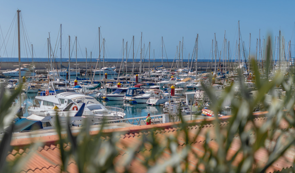 Boote lagen im Hafen von Los Cristianos, Teneriffa, mit dem Meer im Hintergrund.