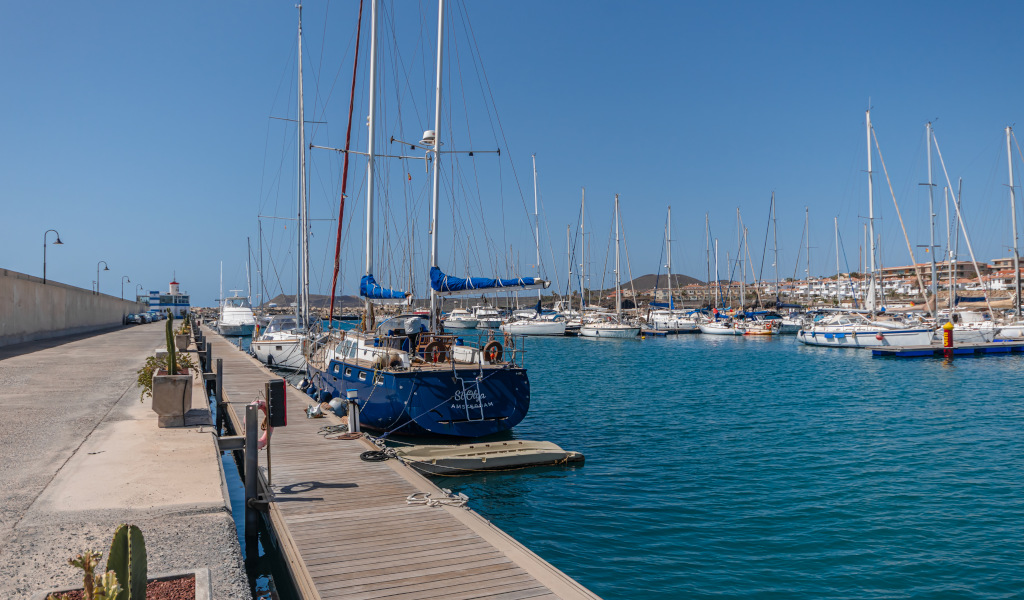 Boote lagen im Hafen von Las Galletas, Teneriffa, mit einem Leuchtturm im Hintergrund.