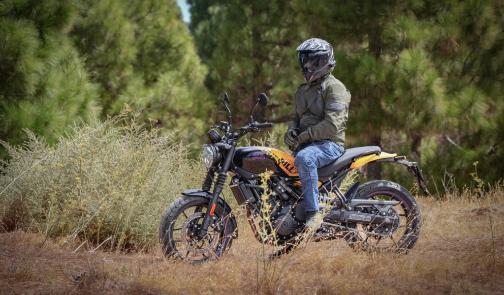 Person, die einen Helm trägt und auf einem Motorrad auf einer Waldstraße auf Teneriffa sitzt.