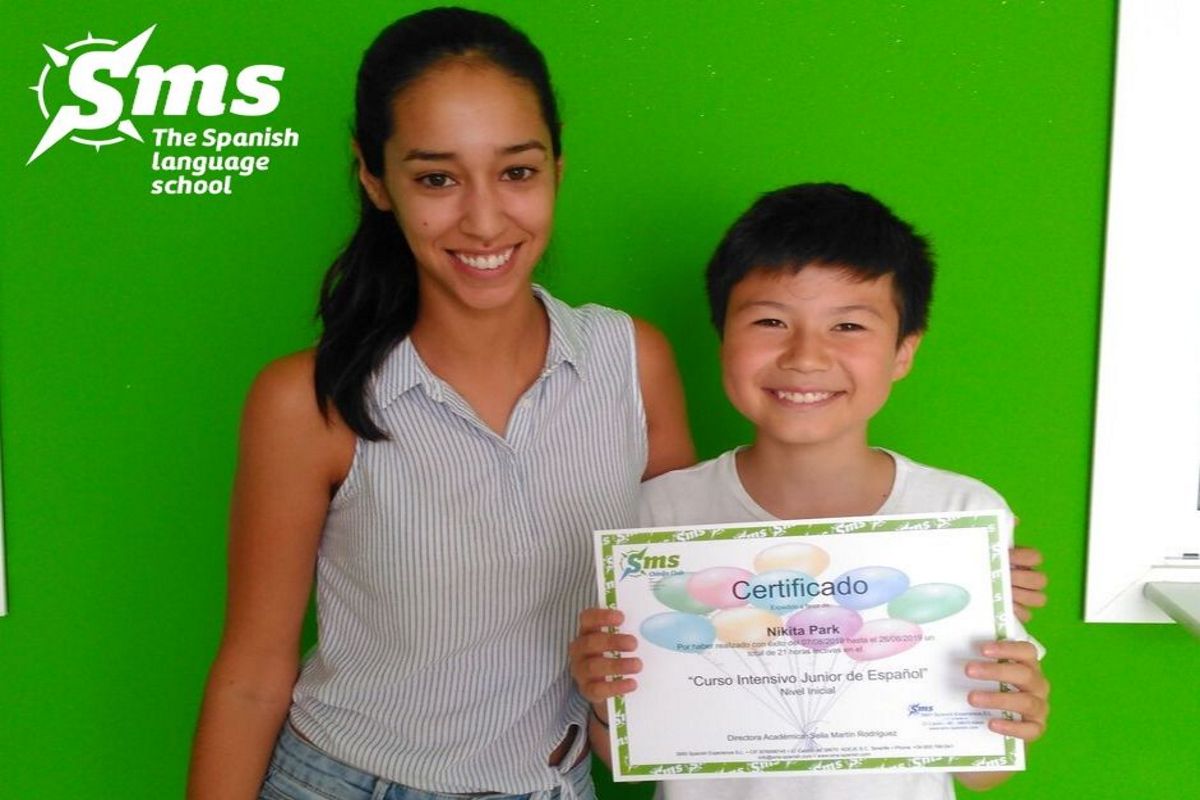 Junge Person mit einem Junior Intensive Spanish Course-Zertifikat auf Teneriffa. SMS-Logo.