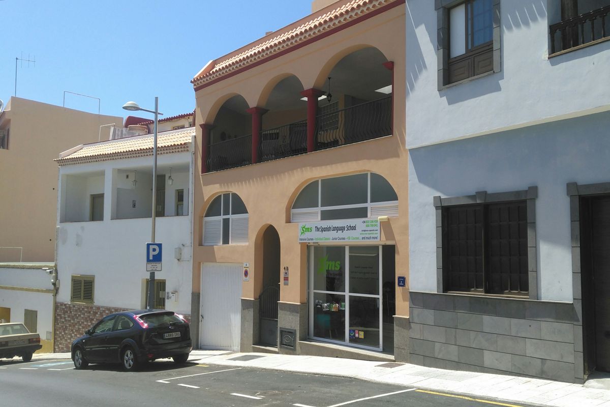 Fassade der spanischsprachigen Schule auf Teneriffa, mit Autos davor.