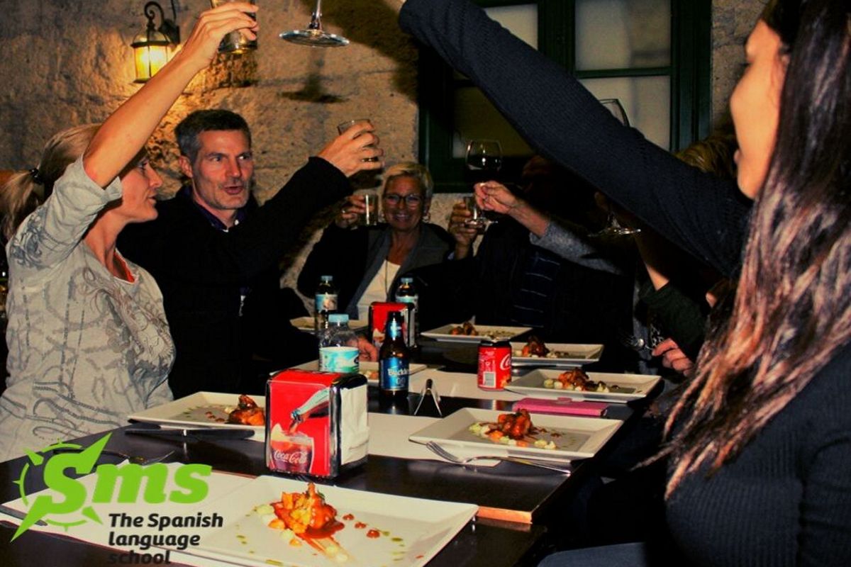 Menschen, die beim Abendessen auf Teneriffa anstoßen, Gerichte mit Essen und Getränken auf dem Tisch.