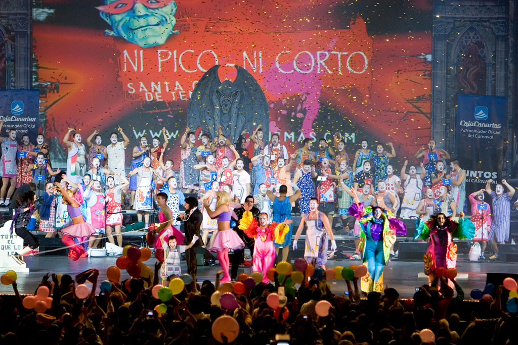 Kostümierte Menschen beim Karneval von Santa Cruz de Tenerife. Enthält den Text WEDER PICO NOCH CORTO.