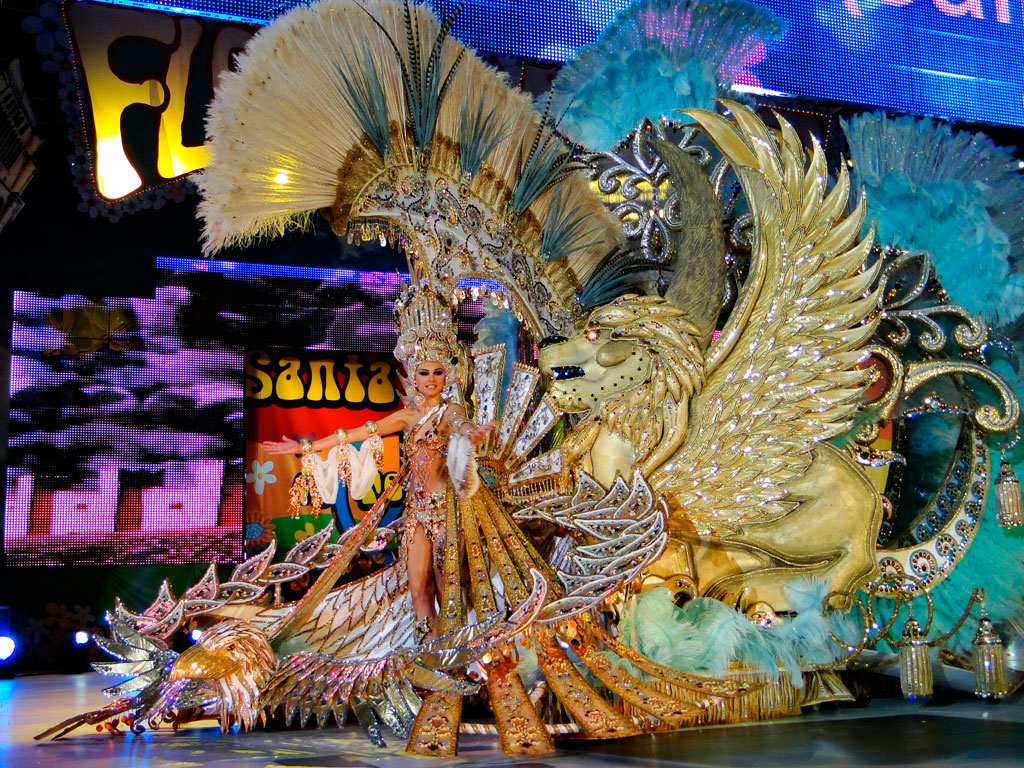 Figur in goldenem Festkostüm mit Federornamenten und geflügeltem Löwe in Santa Cruz de Tenerife.
