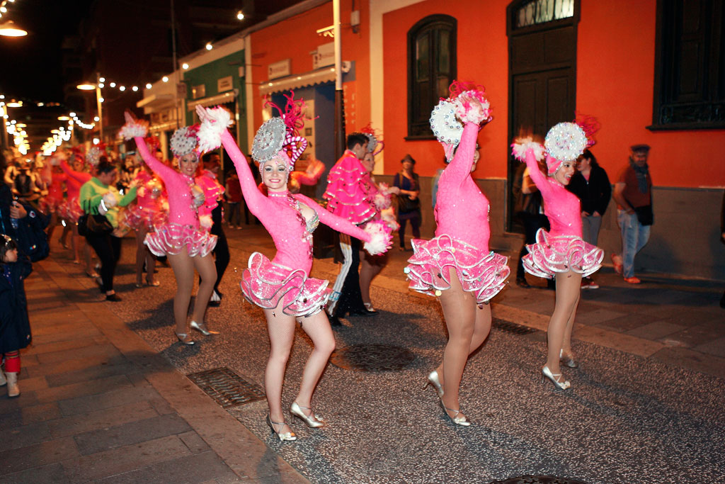 Tänzer in rosa Kostümen paradieren bei einem nächtlichen Karneval auf Teneriffa.