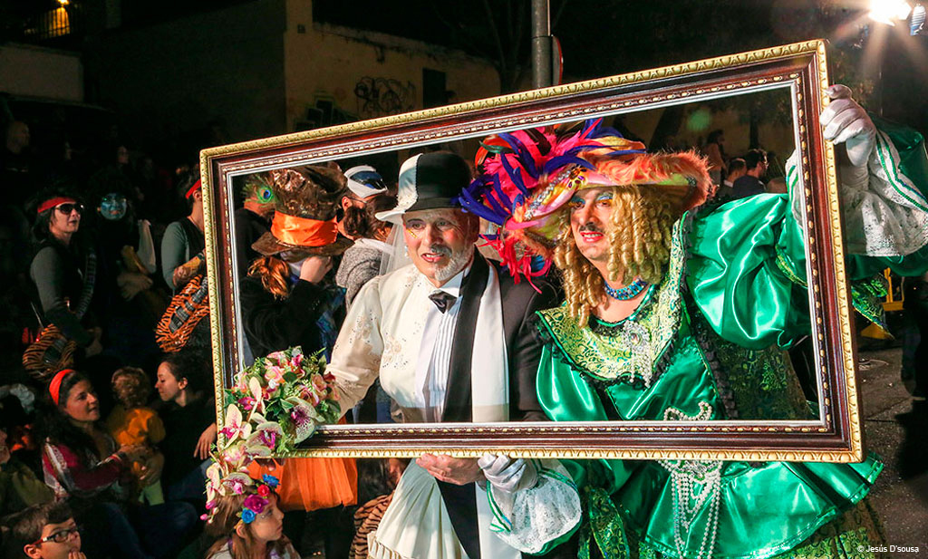 Menschen in bunten Kostümen posieren hinter einem Rahmen beim Karneval auf Teneriffa.