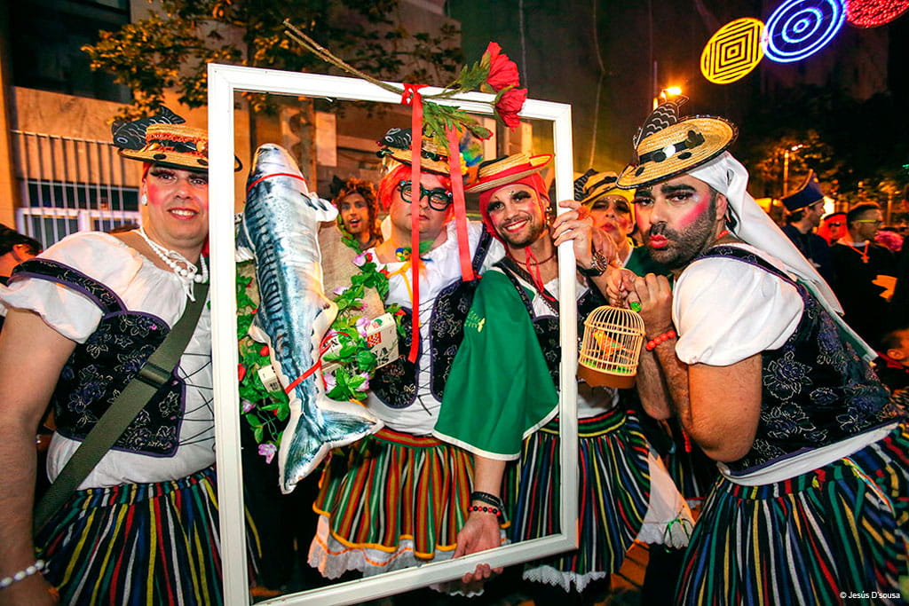 Gruppe beim Karneval auf Teneriffa mit bunten Kostümen und einem geschmückten Rahmen.