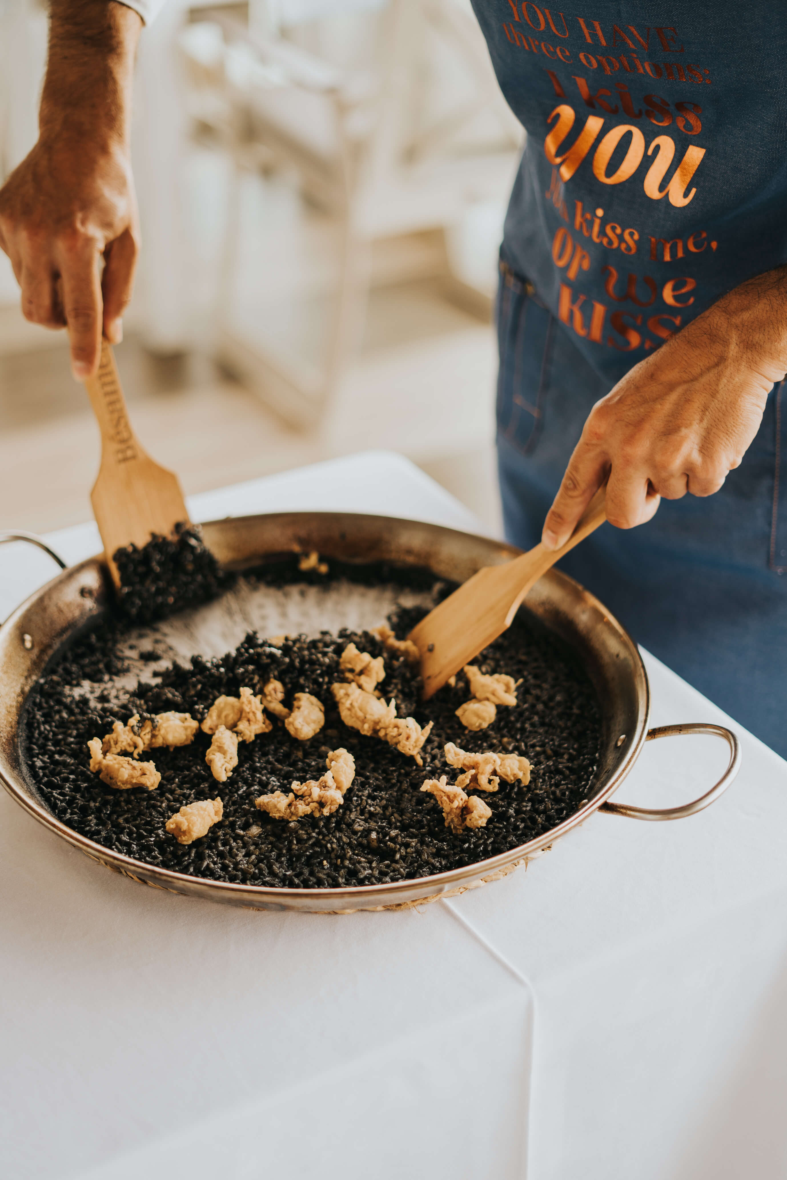Zubereitung von schwarzem Reis mit Meeresfrüchten in einer Paella-Pfanne auf Teneriffa.