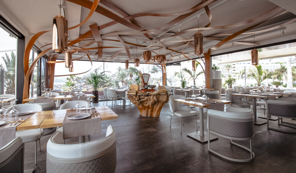 Modernes Restaurant mit eleganter Einrichtung auf Teneriffa, Tische in der Nähe großer Fenster.