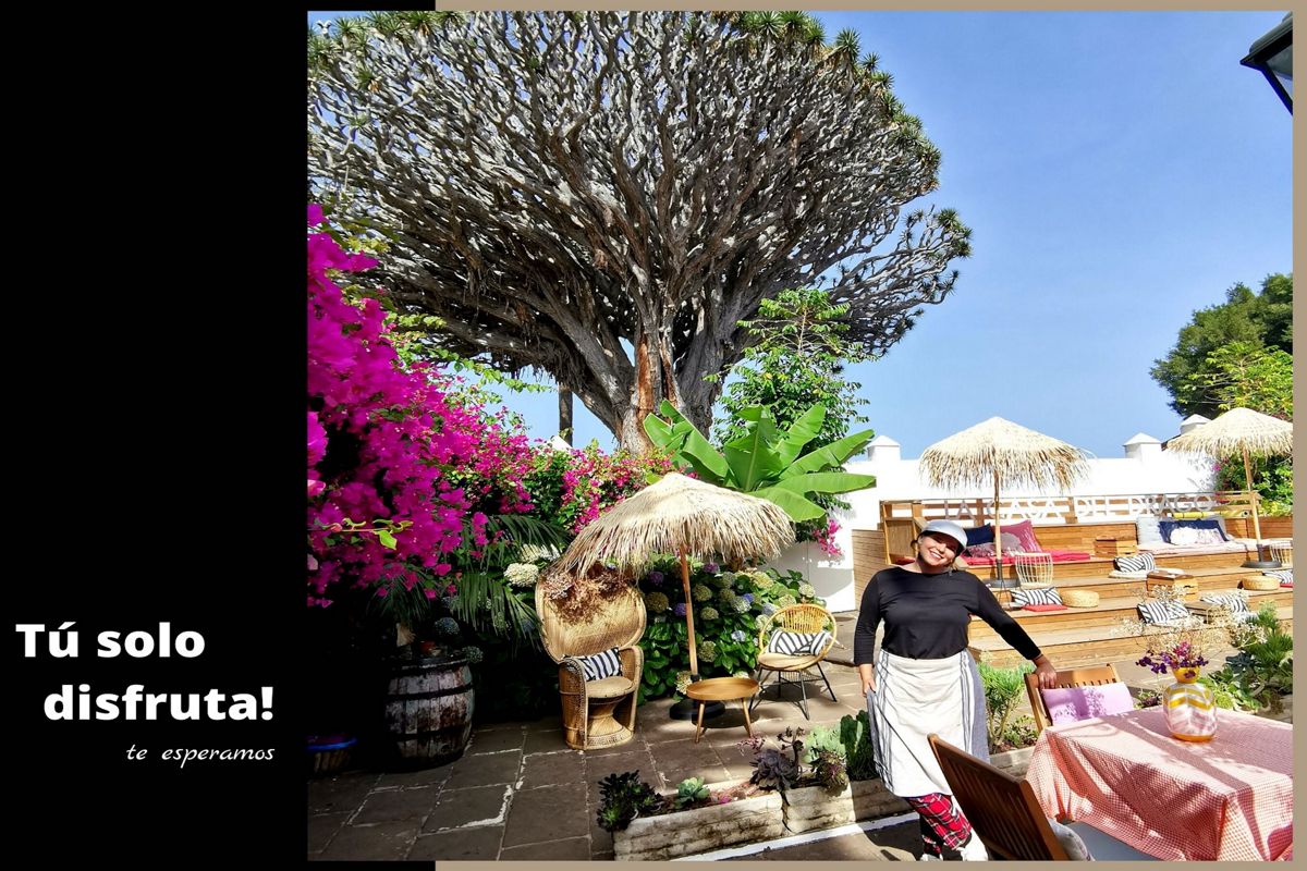 Terrasse mit Vegetation, Strohschirmen und einer Person auf Teneriffa. Text: Genieß es einfach! Wir warten auf dich.