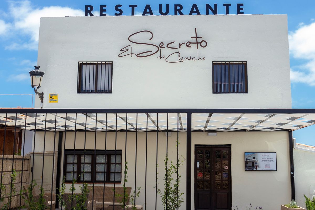 El Secreto de Chimiche Restaurant auf Teneriffa mit einem Schild an einer weißen Fassade.