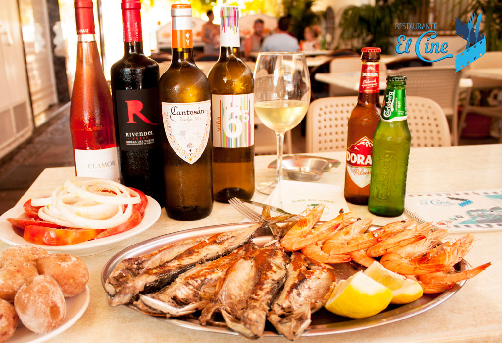 Fisch- und Garnelengericht mit Flaschen Wein und Bier im El Cine Restaurant auf Teneriffa.