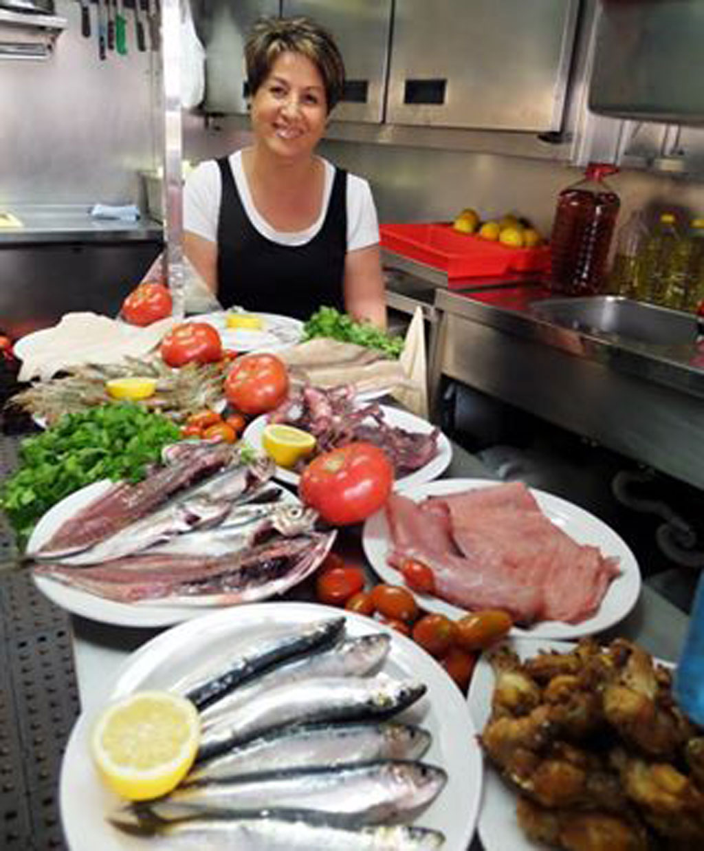 Person in der Küche mit Fisch-, Tomaten- und Zitronengerichten auf Teneriffa.