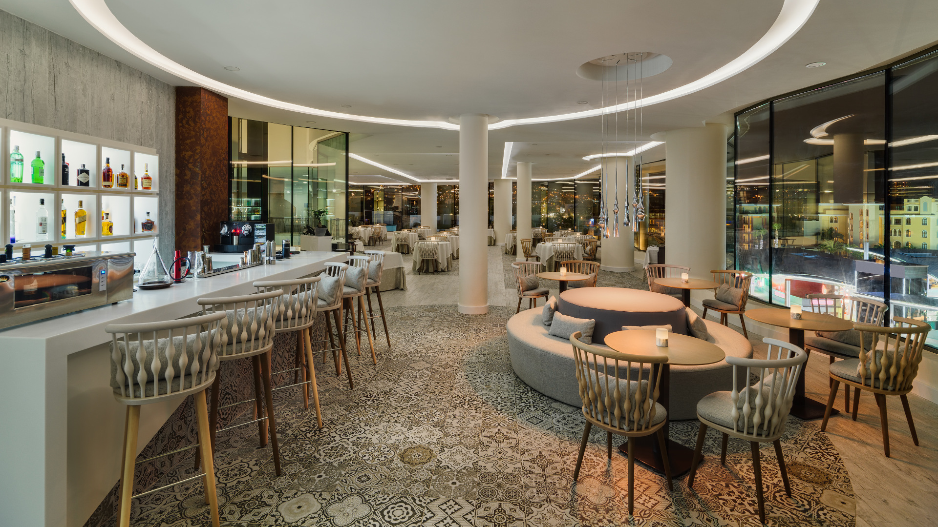 Innenraum eines eleganten Restaurants auf Teneriffa, mit einer beleuchteten Bar und Tischen mit Stühlen.