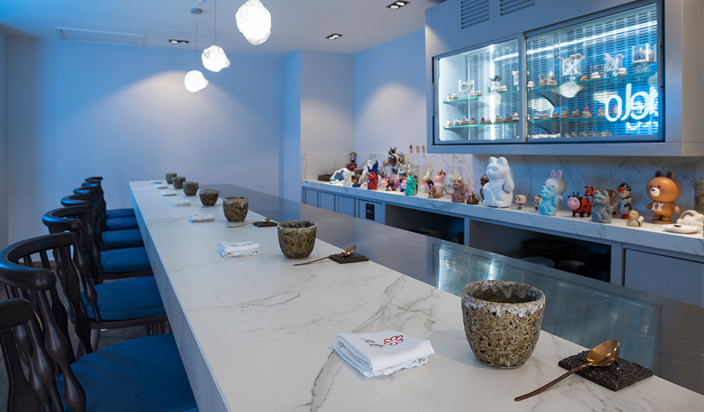Sushi-Bar mit Figurendekoration und blauen Stühlen in einem Restaurant auf Teneriffa.